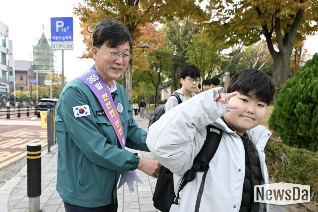 이민근 안산시장(사진 왼쪽)이 학현초등학교 앞에서 ‘스쿨존 어린이 교통안전 캠페인’을 진행하며 등교하는 어린이의 가방에 '홍이 키링'을 달아주고 있다.