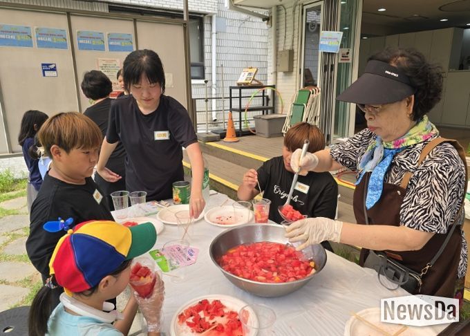'우리마을 은빛 놀이터’프로그램에 참여한 어르신이 아이들에게 수박화채를 나눠주고 있다.