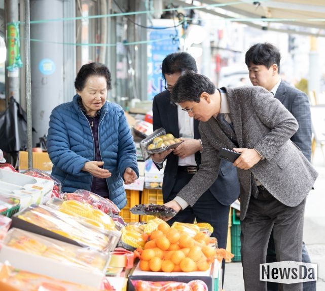 지난달 27일 김돈곤 청양군수가 농어촌 기본소득 지급 첫날 청양 전통시장을 방문해 물품을 구매하며 상인들의 애로사항을 청취하고 있다.