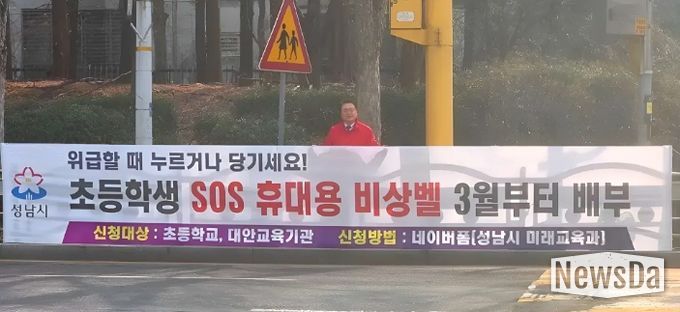 황금석 성남시의원이 초등학교 인근에 설치된 ‘초등학생 SOS 휴대용 비상벨’ 신청 안내 현수막 앞에 서 있다